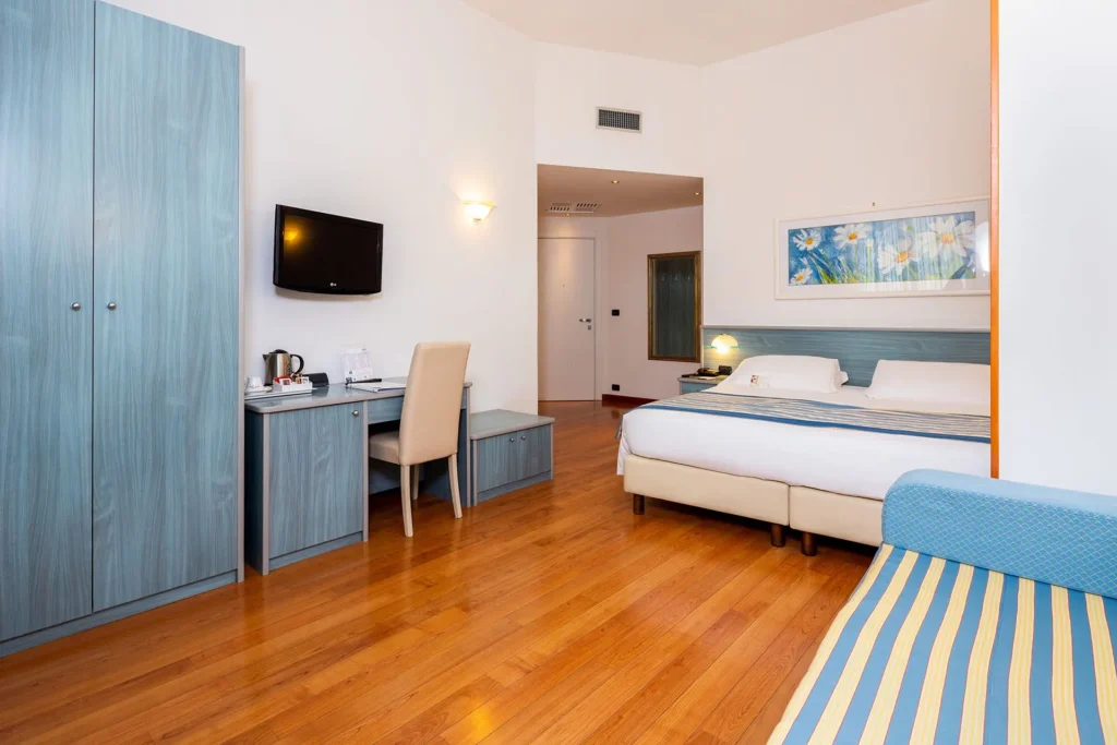 Immagine di una camera superior, con pavimento in legno e arredi azzurri. Sullo sfondo un letto matrimoniale e in primo piano un divano con tessuto a righe